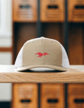 Lima Central Catholic Thunderbird mark snapback hat in khaki resting on an oak bench