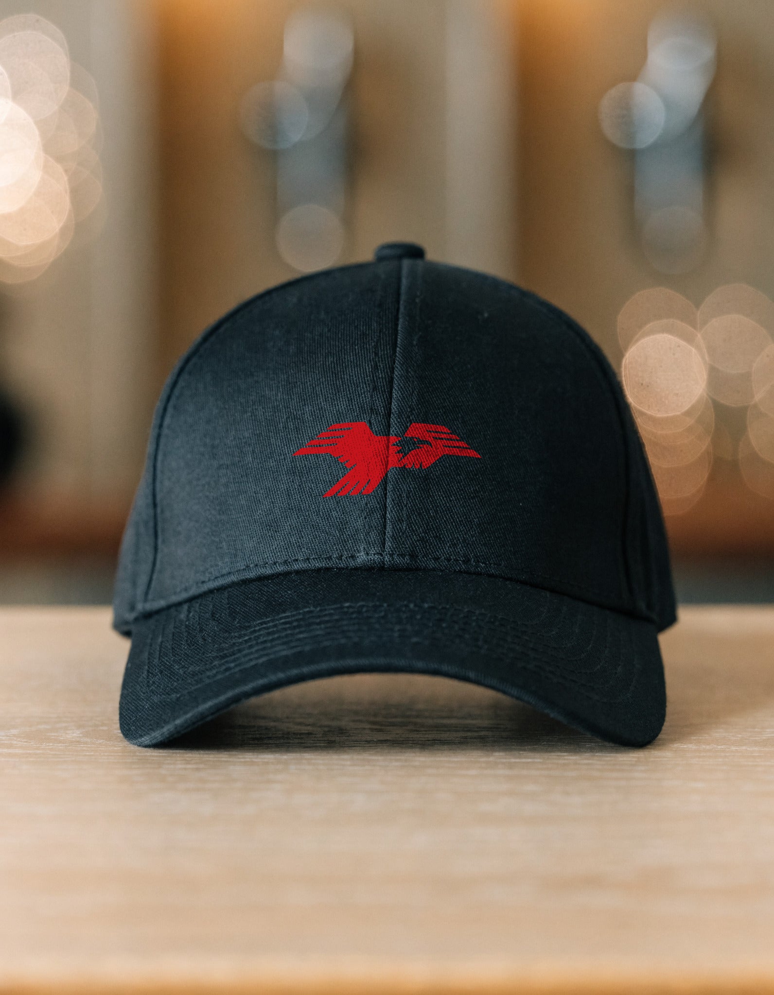 Lima Central Catholic Thunderbird mark stretch fitted hat in black resting on a wood table